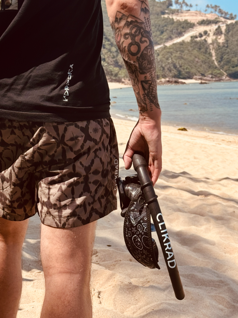 Shorts in the triangle-A monogram pattern, worn on a beach.